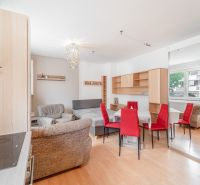 Living space in a one-room apartment with a wooden decor floor, red chairs, and a sofa.