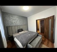 A gray bedroom with a bed and a wooden decor floor in a two-room apartment.