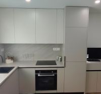 A kitchen in a 3-room apartment with a wooden decor floor and modern cabinets.