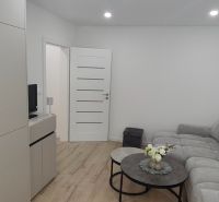 Living room in a three-room apartment with a sofa, tables, and a wooden decor floor.