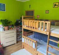 Children's room with a bunk bed, wooden decor flooring, and bright green walls.