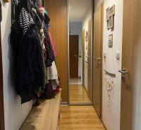 A hallway in a 2-room apartment with coat racks and a mirrored wardrobe, flooring with a wooden decor.