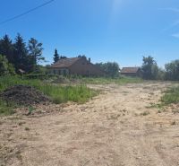 A plot of land for living in Láb with buildings surrounded by greenery and a clear sky.