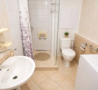 Bathroom in a studio apartment with a bathtub, sink, and washing machine, bright tiles.