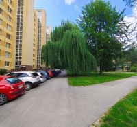 Apartment buildings and parked cars on Sv. Bystríka Street in Žilina, next to the trees.