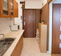 A kitchen in a studio apartment with a built-in unit and ceramic tiles.