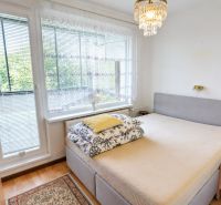 A bedroom in a studio apartment with chandeliers, a bed, and a wooden decor floor.