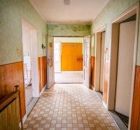 A hallway in a family house with wall cladding and a tiled floor.