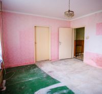 A room in a family house with pink walls and floral patterned curtains.