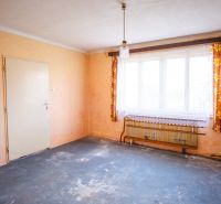 A room in a family house with a worn-out carpet, a window, and curtains.