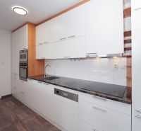 A kitchen in a 3-room apartment with a white kitchen unit and a floor with a wood decor.