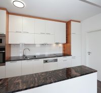 A kitchen in a 3-room apartment with white cabinets and a dark countertop.