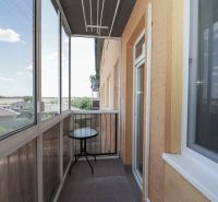 A glazed balcony with a view of rooftops and the sky, in a 3-room apartment.