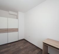 A room with a white wardrobe and a wooden decor floor in a 3-room apartment.