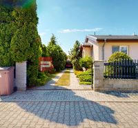 A family house in Senec with a well-maintained garden and an access road made of paving stones.