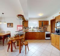 A kitchen in a family house with a dining table, a bar counter, and wooden cabinets.