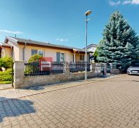 A family house in the village of Tureň with a garden, paved road, cars parked in front of the house.