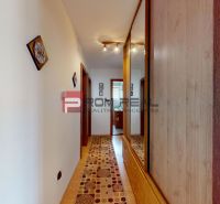 A hallway in a family house with a wooden decor floor and a mirrored wardrobe.