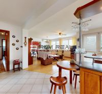 Kitchen and living room in a family house with a wood-patterned floor and floral decorations.