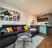Living room with a leather sofa, pictures on the wall, and a wooden decor floor.