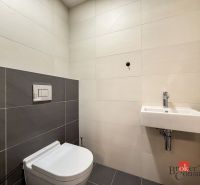 Bathroom with toilet and sink in a 2-room apartment with tiling.