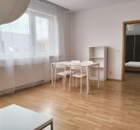 2-room apartment with wood-patterned flooring, white table with transparent curtains.