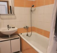 A bathroom in a 2-room apartment with a bathtub and orange-white tiles.