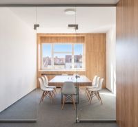 Office with glass doors, wooden decor flooring, white desk and chairs.