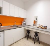 Offices with a kitchenette, white cabinets, an orange wall, and a wood-patterned floor.