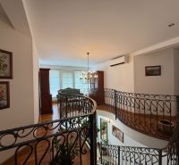 Charming staircase with wrought iron railing and wood-decor flooring in a family house.