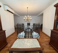 Interior of a family house with a wooden-patterned floor and a staircase with a railing.