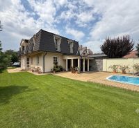 A family house in Senec with a garden, a swimming pool, and a manicured lawn under a blue sky.