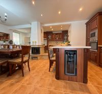 A spacious kitchen with a fireplace and wooden furniture in a family house.