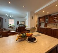 The kitchen and dining room in a family house with wooden decor furniture and central lighting.