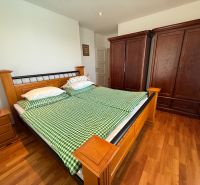 A bedroom in a family house with a wood-patterned floor, wooden furniture, and green bed linen.