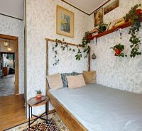 Bedroom in a 2-room apartment with a bed, plants, and decorative shelves.