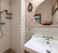 Bathroom in a 2-room apartment with white tiles and a round mirror.