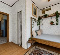 2-room apartment with wood-patterned flooring, houseplants, and white wallpaper.
