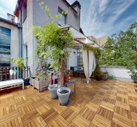 A terrace with plants, wooden decor, curtains, and garden furniture in a 2-room apartment.