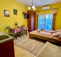 Interior of a holiday apartment with a wood-decorated floor, dining table, and bed.