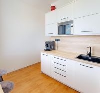 A kitchen in a 2-room apartment with white cabinets and a floor with a wood decor.