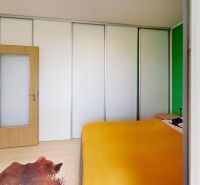 Bedroom in a 2-room apartment with a large wardrobe and a wooden decor floor.
