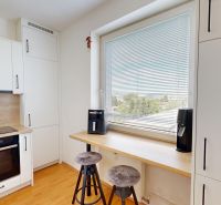 A kitchen in a 2-room apartment with white cabinets and a wood-patterned floor.