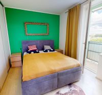 Bedroom in a 2-room apartment with a bed, green wall, and access to the balcony.