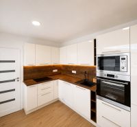 Bright kitchen in a 2-room apartment with wood-patterned flooring and built-in appliances.