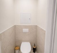 A bathroom with a simple design in a two-room apartment with beige tiles.