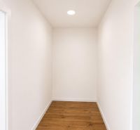 A hallway with white walls and a wooden decor floor in a 2-room apartment.