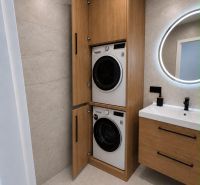 Stylish bathroom in a 2-room apartment with a washing machine and dryer in wooden decor.