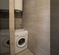 Washing machine and boiler in the bathroom of a two-room apartment with tiled walls.