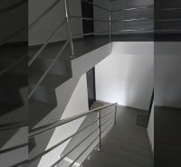The interior of a staircase with a metal railing and gray flooring in a 2-room apartment.